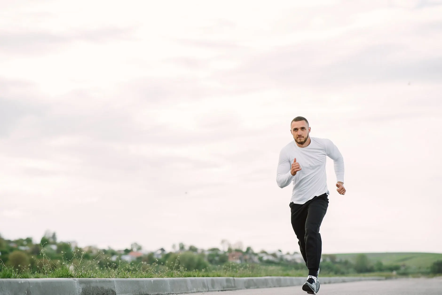 A man running alone on an empty road in casual sportswear.