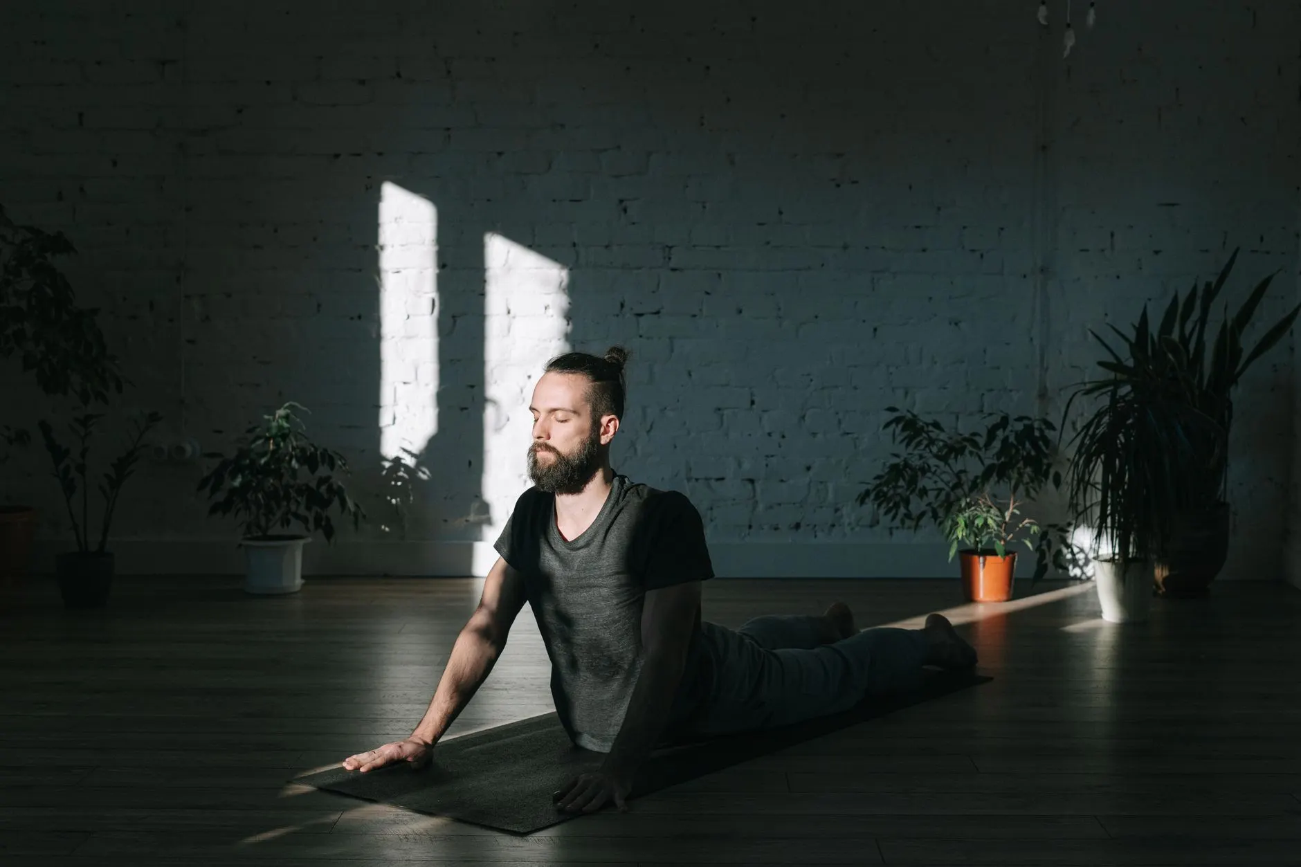 A man meditating indoors in soft sunlight.