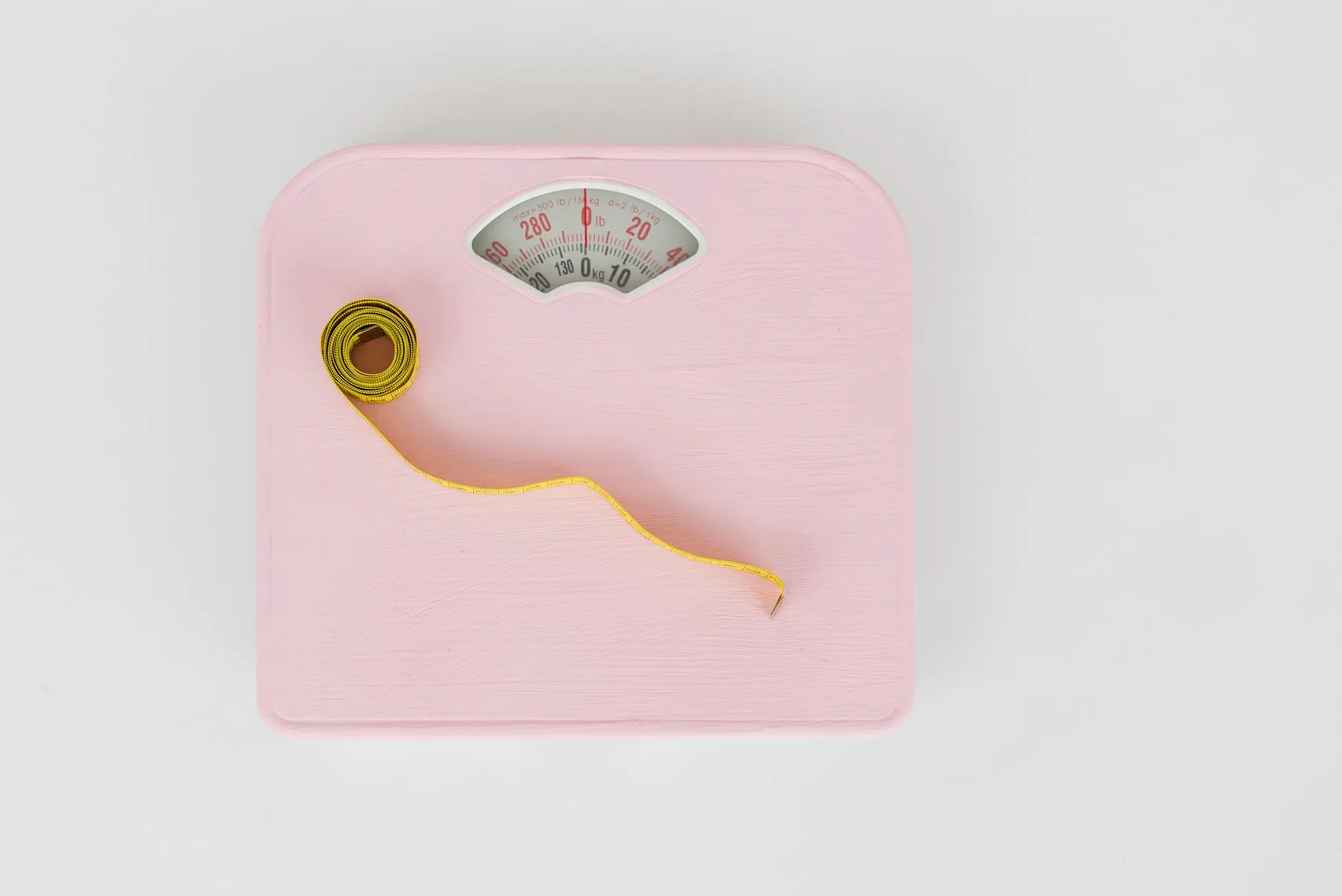 A bathroom scale and a measuring tape on a white background.